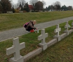 Powiększ zdjęcie Uczennica zapala znicz na grobie żołnierza