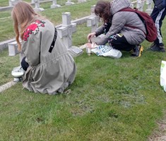 Powiększ zdjęcie Uczniowie zapalają znicze na grobach żołnierzy