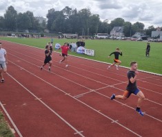 Powiększ zdjęcie Zawodnicy kończą bieg na 100m. W czarnej koszulce z długim rękawem - Maksymilian Woś